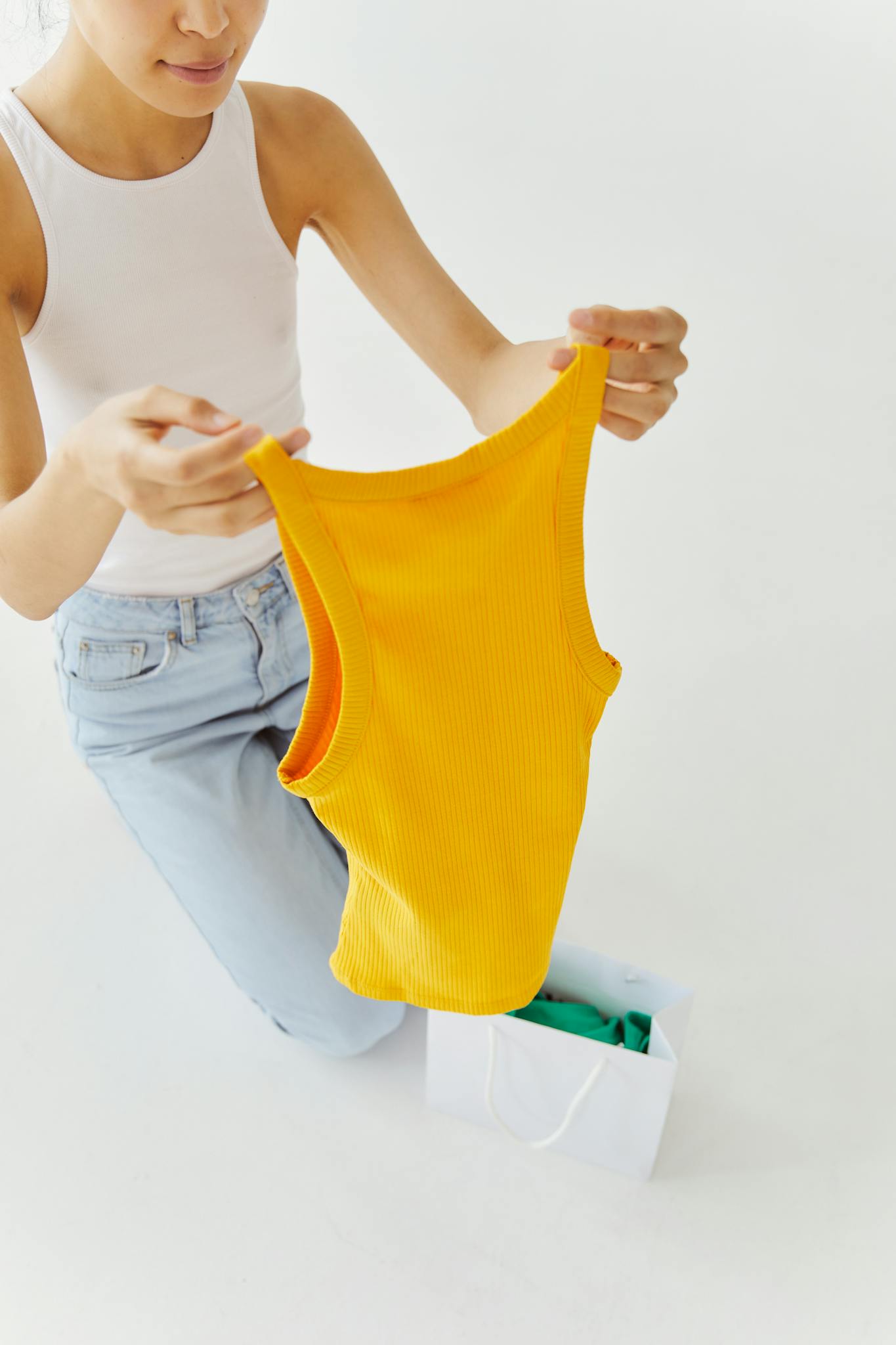A Woman Examines A Yellow Tank Top